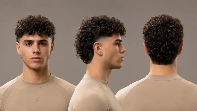 Man with a textured burst fade mullet hairstyle featuring sharp faded sides, messy volume on top, and longer layered hair in the back for a modern edgy look